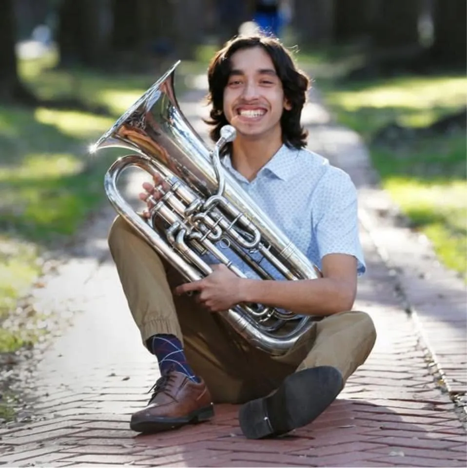 Miguel in 12th grade, seated with his euphonium